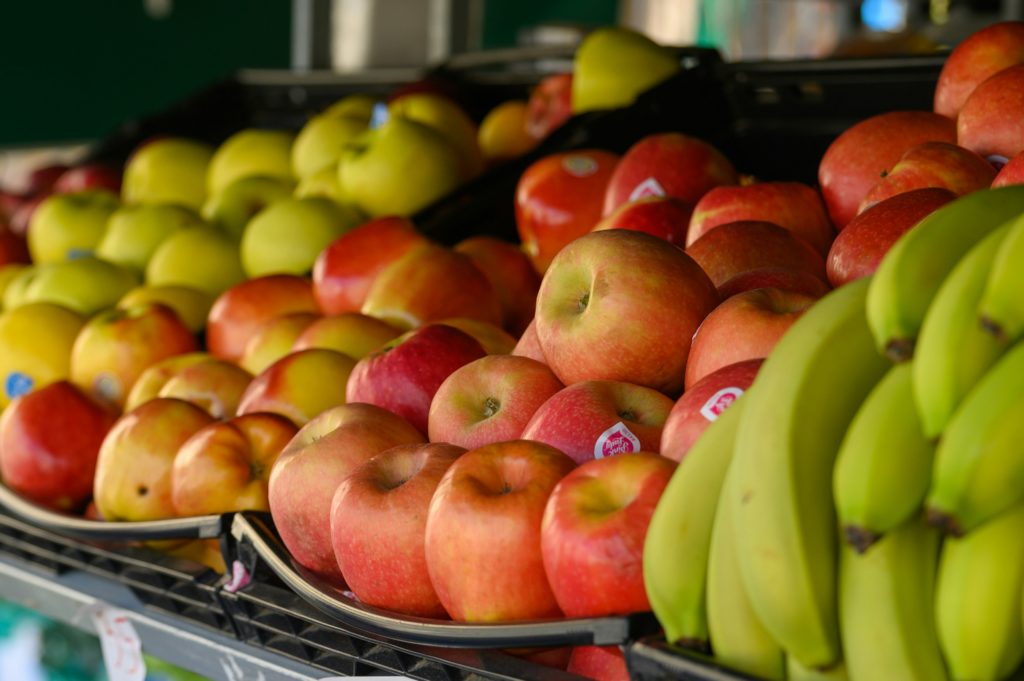 Experienced greengrocer arranging fresh produce at premium supermarket in Notting Hill
